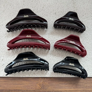 Macro shot of large and small crescent hair claws in burgundy, red, and black finishes