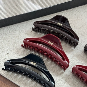 Detailed macro view of high-gloss polished crescent hair claw clips in three elegant colors