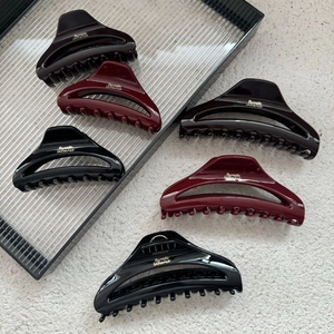 Detail showing high-gloss crescent hair claw clips in black, burgundy and brown tones