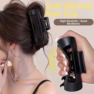 Détail macro de la grande pince à cheveux en silicone noir mat montrant sa grande flexibilité