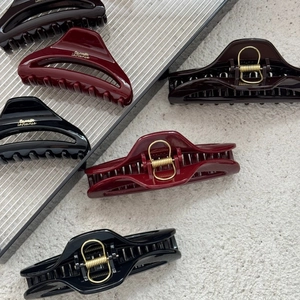 Detailed view of large black and burgundy crescent hair claws with gold metal springs