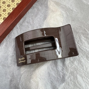 Détail d'une pince à cheveux léopard marron foncé avec logo doré et rayures ajourées