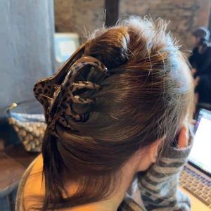 Rear view of large leopard print hair claw clip worn on thick hair in a cafe setting
