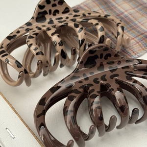Detail of leopard print hair claws with octopus-style teeth and glossy finish on plaid fabric