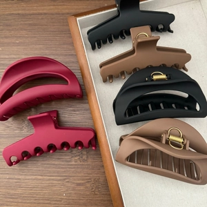 Gros plan de pinces à cheveux en silicone mat noir, marron et bordeaux sur bois