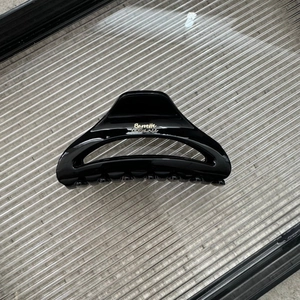 Close-up of glossy black crescent hair claw clip featuring golden cursive text detail
