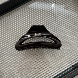 Detail view of large dark resin hair claw clip with golden Barrette La France lettering