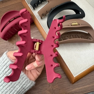 Détail d'une pince à cheveux mate rose avec ressort doré et dents de préhension solides