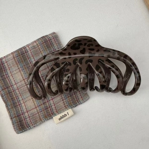 Close-up of a deep brown leopard print octopus hair claw clip on a textured fabric cloth