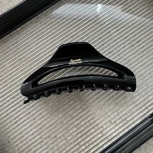 Detail of glossy black moon-shaped hair claw clip with golden Barrette La France text
