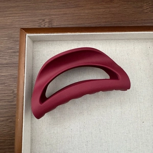 Vue détaillée d'une grande pince à cheveux bordeaux mat avec une texture gommée