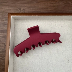 Détail macro d'une grande pince à cheveux bordeaux mat avec dents solides pour cheveux épais