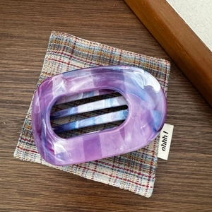 Vue détaillée de la pince à cheveux en acétate marbré violet avec motif ovale et griffes
