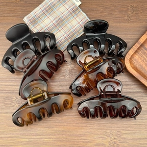 Elegantes Set aus großen Haarklammern in Schwarz und Schildpatt auf einem Holztisch