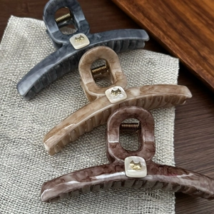 Detailed view of marble-textured large hair claws with golden dog logo accents
