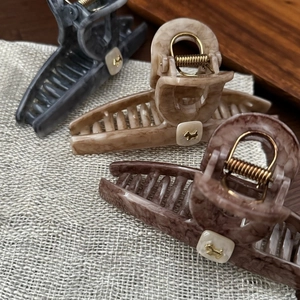 Detailed view of large marble texture hair claws featuring golden dog design motifs