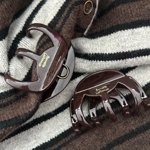 Gros plan de pinces à cheveux en résine marron avec texte doré sur un pull en maille