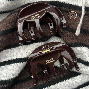 Pince à cheveux en résine marron poli avec lettrage doré sur fond de tricot