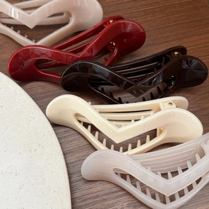 Close-up of minimalist heart-shaped resin hair claws in five colors on a wood surface