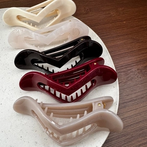 Large V-shaped heart hair claw clips in five colors on a wooden background