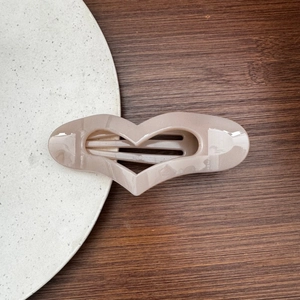 Close-up of large heart-shaped hair clip with elegant beige marble pattern texture