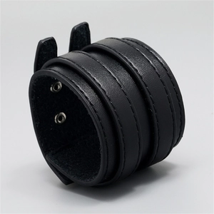 Detail eines mehrlagigen schwarzen Lederarmbands im Punk-Stil mit Nähten und Druckknöpfen