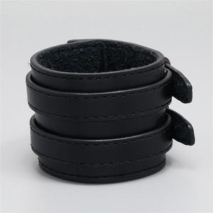 Nahaufnahme eines dreilagigen schwarzen Lederarmbands im Punk-Stil mit Schnallen und Naht