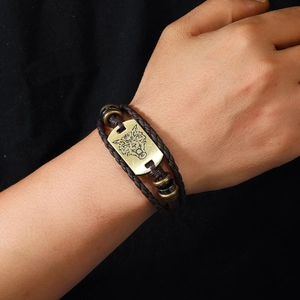 Detail of brown braided leather wolf head bracelet on male wrist with retro metal beads