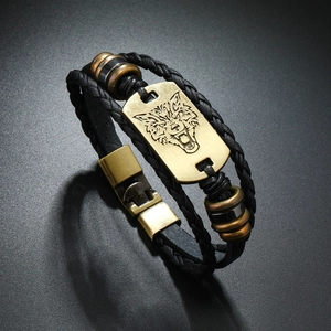 Macro detail of men's multilayer braided leather bracelet with vintage wolf head metal plate