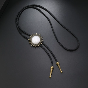 Makro-Detail des goldenen Bolo-Tie-Anhängers mit Sonnenstrahl-Design und geflochtener Kordel