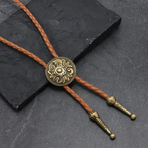 Detail of vintage gold bolo tie slide with floral relief on dark rocky background
