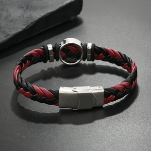 Détail du bracelet en cuir tressé rouge et noir avec fermoir et disque en métal brossé