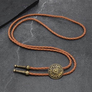 Close-up of vintage bolo tie with floral brass buckle and braided leather cord