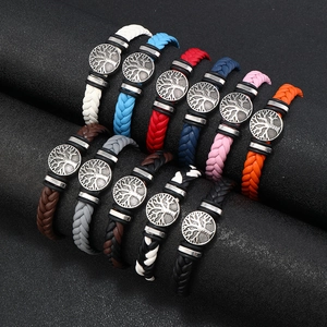 Men's leather braid bracelet with tree of life charm in multiple colors displayed on a stand