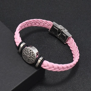 Detailed close-up of pink braided leather bracelet with tree of life charm and steel clasp