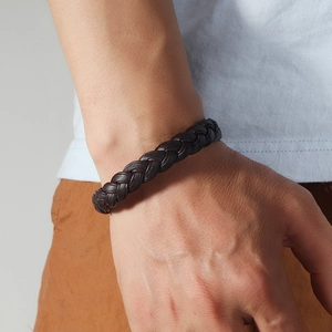 Close-up of a braided dark brown leather bracelet worn on a man's wrist for fashion