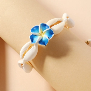 Detail of bohemian shell bracelet featuring a central yellow and blue plumeria flower
