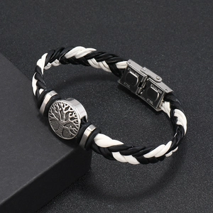 Detail of braided leather bracelet with stainless steel tree of life clasp on dark background