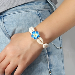 Bohemian cowrie shell bracelet with blue gradient flower on denim background