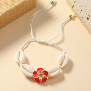 Close-up of tropical shell bracelet with white plumeria flower and adjustable woven cord