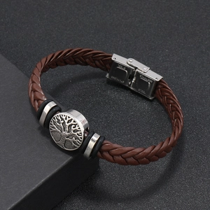 Detailed close-up of brown braided leather bracelet with stainless steel tree of life clasp