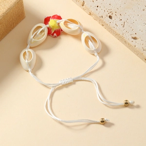 Detail of woven shell bracelet with red floral center and adjustable gold beads