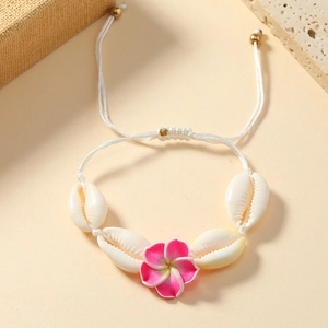 Detail of bohemian handmade shell bracelet with pink Frangipani flower and white cord