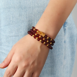 Naturgranat Armband mehrlagig mit goldenem PiXiu Glücksbringer auf blauem Denim
