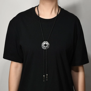 Detail of vintage silver bolo tie featuring a sun pattern floral design with a black gemstone