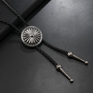 Detail of vintage silver flower bolo tie with black braided leather and engraved metal tips