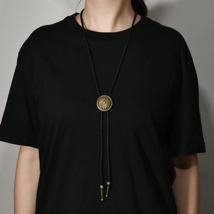 Vintage sunburst bronze bolo tie with black braided cord shown on male model neck