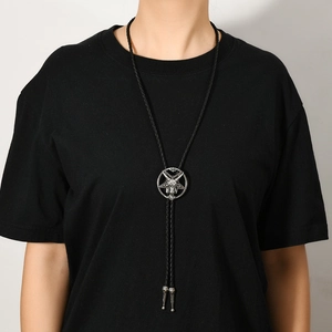 Macro shot of a silver gothic Baphomet star bolo tie on a black shirt with woven cord