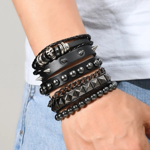 Detail of multi-layer punk bracelet with leather cords, metal studs, and a silver skull charm