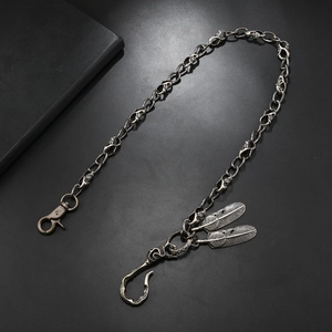 Detailed macro view of vintage skull links and silver feather pendants on a biker chain